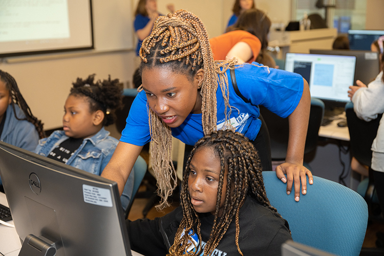 Middle Tennessee State University information systems and analytics majors Jennifer Nanmejo, a native of the central African nation of Gabon, standing, gives instructions to a young participant attending the "Code Like a Girl" camp on April 15 in the Business and Aerospace Building. (MTSU photo by James Cessna)