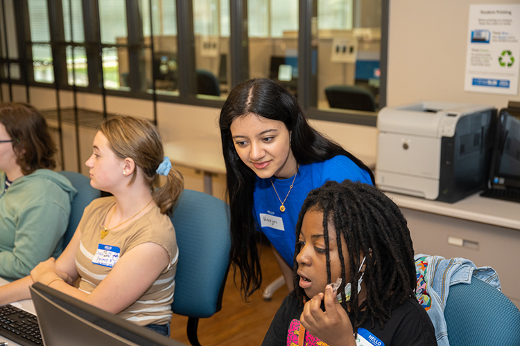 Middle Tennessee State University information systems and analytics major Havjin Barkhan of Nolensville, Tennessee, center, helps a young participant during the "Code Like a Girl" camp on April 15 at the Business and Aerospace Building. (MTSU photo by James Cessna)