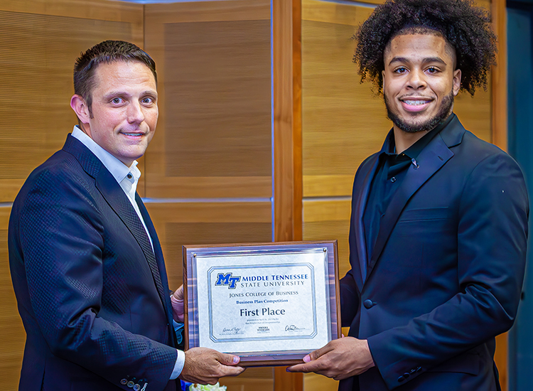 MTSU rising senior aerospace technology and mathematics major Mervyn Thomas-Crawford of Baltimore, Md., accepts the first-place plaque from Joshua Aaron, chairholder of the Wright Chair of Entrepreneurship and competition organizer, during the 2023 Business Plan Competition Finals held April 26 in the Student Union Parliamentary Room at Middle Tennessee State University. Thomas-Crawford also received $9,000 for capturing the top spot. (MTSU photo by Tom Beckwith)