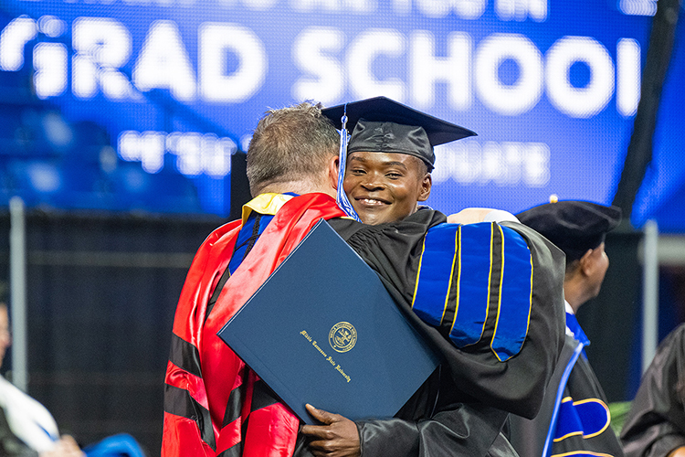 Abigail Kwarteng, right, Middle Tennessee State University graduate student and Olympic hopeful, hugs David Butler, dean of MTSU’s College of Graduate Studies, after accepting her master’s degree in public health at MTSU’s afternoon spring commencement ceremony Saturday, May 6, inside Murphy Center. (MTSU photo by Cat Curtis Murphy)