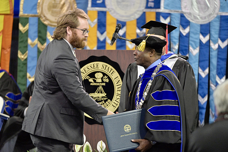 Metro Nashville Police Department detective Ryan Cagle, left, accepts his honorary professorship in public safety certificate from MTSU President Sidney A. McPhee at the university’s spring commencement ceremony Friday, May 5, in Murfreesboro, Tenn. A total of five officers received the honor for their heroic response to the Covenant School shooting in Nashville, Tenn., in late March. (MTSU photo by Andy Heidt)