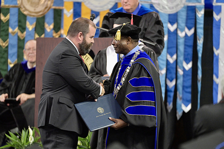 Metro Nashville Police Department Sgt. Jeffrey Mathes, left, accepts his honorary professorship in public safety certificate from MTSU President Sidney A. McPhee at the university’s spring commencement ceremony Friday, May 5, in Murfreesboro, Tenn. A total of five officers received the honor for their heroic response to the Covenant School shooting in Nashville, Tenn., in late March. (MTSU photo by Andy Heidt)