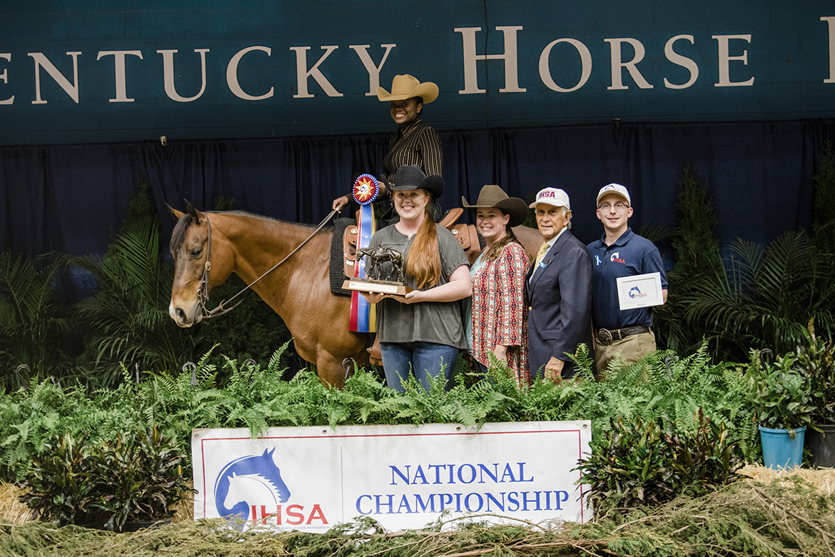 Aboard a horse named Flint, Sadio Barnes of Miami, Florida, is shown after her National Champion ride in Team Beginner Horsemanship at the Intercollegiate Horse Shows Association national competition at Kentucky Horse Park in Lexington, Ky. Also pictured are coach Ariel Higgins, left, assistant coach Andrea Rego, IHSA founder Bob Caccione and an awards presenter. (Photo by EQ Media)