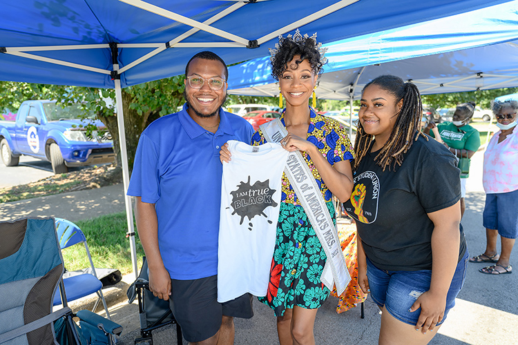 United States of America Mrs. 2022 and MTSU alumna LaShan Dixon, center, accepts a T-shirt from Office of Intercultural staffer Jalen Mims, left, and a student member of the MTSU Blue Student Union at the 2022 Juneteenth Festival in Murfreesboro, Tenn. Middle Tennessee State University will again have representatives staffing information tables at the 2023 street festival Saturday, June 17. (MTSU file photo by James Cessna)