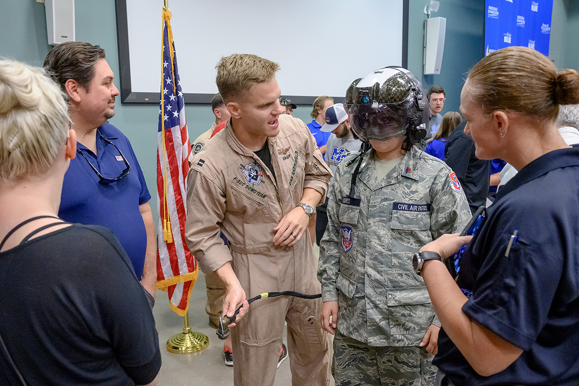 U.S. Navy F-35C Demo Team member Lt. Dan “Skap” Barringer, center, lets Cody Jones, 12, of Smyrna, Tenn., try on one of the $100,000 helmets the F-35C pilots use when flying. They and Navy Blue Angels pilots and personnel spoke Friday, June 9, at Middle Tennessee State University to a gathering of students, faculty, staff and visitors assembled in a College of Education building classroom. (MTSU photo by J. Intintoli)