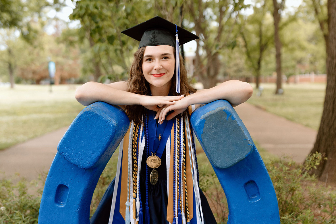 In this spring photo, Catheryn Bolick, a spring Middle Tennessee State University honors graduate from Smyrna, Tenn., stands behind the blue horseshoe wearing her academic regalia in Walnut Grove. Bolick is one of 62 recipients nationwide to receive Phi Kappa Phi Fellowship for 2023. She will pursue a doctorate in cancer cell biology at Washington University in St. Louis, Mo. (Submitted photo)