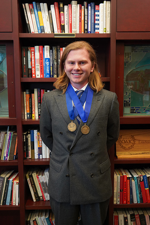 Shown here inside the Paul W. Martin Sr. Honors Building wearing two of his academic medallions, Middle Tennessee State University spring 2023 honors graduate Benjamin Adams of Murfreesboro, Tenn., recently completed the Intercollegiate Studies Institute’s 2023 Honors Conference in Annapolis, Maryland. Adams graduated with a bachelor’s degree in political science and international relations with minors in Honors and pre-law. (Photo by Connie Bartemus, MTSU Honors College)