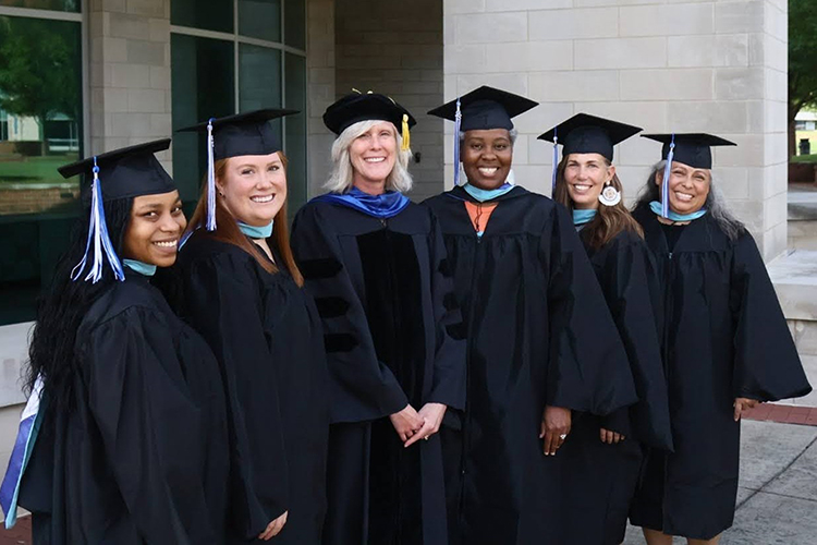 Recent graduates of Middle Tennessee State University and members of the “Grow Your Own” grant cohort, educational assistants who received funding from the Tennessee Department of Education to become licensed special education teachers, along with Robyn Ridgley, third from left, the College of Education’s associate dean, take a photo outside the College of Education building on campus in their graduation robes on Aug. 4, 2023. Pictured, from left, are Ariel Davie, Bre Clark, Ridgley, Nichelle Shelton, Brittany Jackson and Ruth Gonzalez-Hill. (Submitted photo)