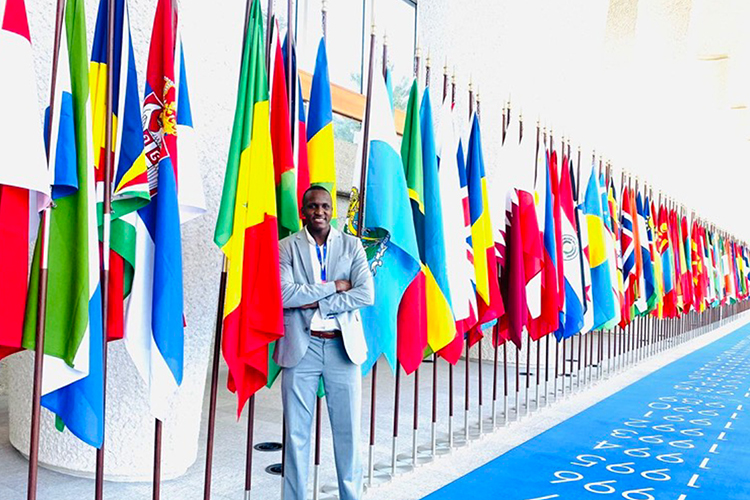 Baye Sambou, alumnus of Middle Tennessee State University’s international affairs graduate program, smiles for a photo in a hallway of flags on his first day as a technical officer at the International Labour Organization in Geneva, Switzerland. (Submitted photo)