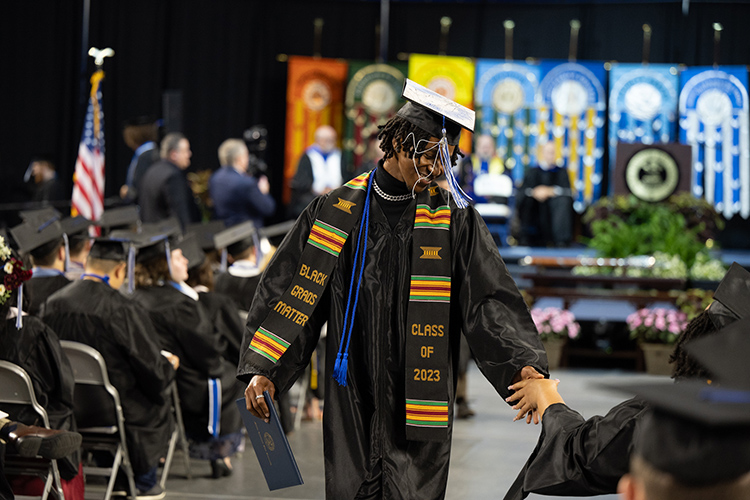 Diploma cover in hand, a proud Middle Tennessee State University graduate shakes hands with a classmate before returning to his seat during the summer 2023 commencement ceremony held inside Murphy Center on the MTSU campus in Murfreesboro, Tenn. (MTSU photo by James Cessna)