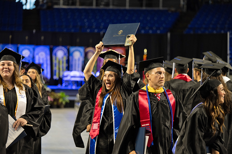 A proud student-veteran, wearing the special red veterans stole, proudly holds up her diploma cover during the summer 2023 commencement ceremony held inside Murphy Center on the MTSU campus in Murfreesboro, Tenn. (MTSU photo by James Cessna)