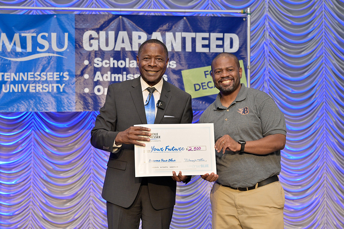 Middle Tennessee State University President Sidney A. McPhee, left, takes a photo with Blackman High School counselor Marcus Lyons and the $2,500 ceremonial scholarship checks that McPhee presented to Lyons and 20 other counselors at a True Blue Tour kickoff appreciation luncheon held Sept. 13 in the university’s Student Union Ballroom. McPhee unveiled the new High School and Community College Counselor Scholarships program that provides attending counselors on the tour stop luncheons in Tennessee with funds to disburse to one of more of their students looking to attend MTSU. (MTSU photo by Andy Heidt)