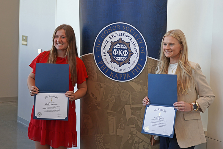Middle Tennessee State University student Hailey Harrison, an aerospace major, left, and Clair Quillen, a professional studies major, pose in front of a Phi Kappa Phi banner with their certificates after the fall induction ceremony Oct. 20, 2023, on campus. (MTSU photo by Robin E. Lee)