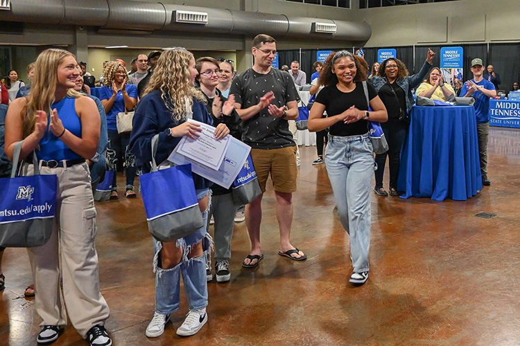 niah Kidd smiles on her way to accept her scholarship win during a drawing at Middle Tennessee State University’s True Blue Tour recruitment stop for prospective students at the Wilma Rudolph Event Center in Clarksville, Tenn., on Thursday, Sept. 28, 2023, as her mother, hands raised, cheers her on in the background. (MTSU photo by Stephanie Wagner)
