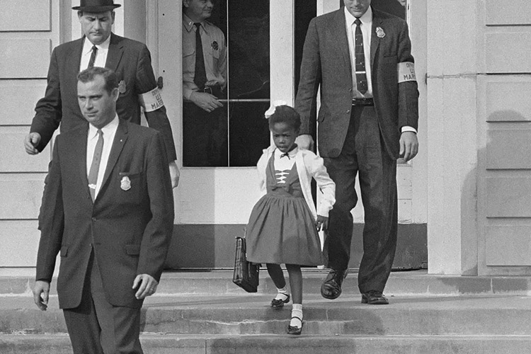 U.S. Marshalls escort 6-year-old Ruby Bridges through the doors of William Frantz Elementary School, in New Orleans, Louisiana, on Sept. 8, 1960. She became the first Black student to attend an all-white elementary school in the Southern United States. (Photo courtesy AP)