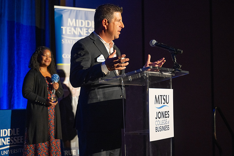 Middle Tennessee State University alumnus John Cipriano gives remarks as recipient of the 2023 Jennings A. Jones Champion of Free Enterprise Award from the Jones College of Business during a special ceremony Oct. 19, 2023, at Embassy Suites in Murfreesboro, Tenn. In the background is Yolanda Greene, Rutherford County community bank president for event sponsor First Horizon Bank. (MTSU photo by Cat Curtis Murphy)