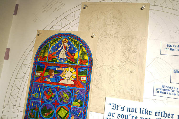 Sketches and sample drawings of Middle Tennessee State University Honors student Eli Ward’s work are shown before the painting on translucent paper took place. They were part of Ward’s thesis exhibit displayed during the fall semester inside Todd Art Gallery at MTSU. By painting on translucent paper, Ward was able to replicate a stained-glass appearance with lights behind hanging white sheets, imitating windows. (Photo by Robin E. Lee)