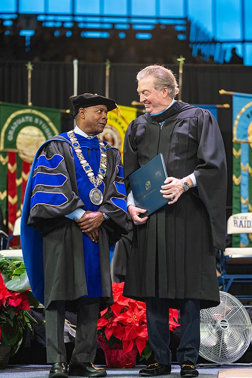 Middle Tennessee State University President Sidney A. McPhee smiles at local developer and philanthropist John Floyd, who was presented a special honorary doctorate degree — only the seventh awarded by the institution in its 110-plus years — during the morning commencement ceremony Dec. 16 at Murphy Center. More than 1,760 undergrad and graduate degrees were awarded to the final Class of 2023. Floyd said 50% of his sales staff were part of the Blue Raider Real Estate Club while earning degrees from MTSU. (MTSU photo by Cat Curtis Murphy)