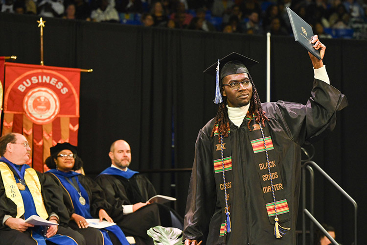 Byron Bankhead, who earned a Bachelor of Social Work, holds up his diploma as he walks across the stage at Murphy Center during the Class of 2023 fall commencement ceremonies. MTSU presented more than 1,761 undergrad and graduate degrees to students in two ceremonies held Dec. 16. (MTSU photo by Cat Curtis Murphy)