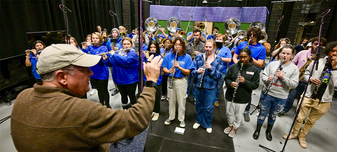 Craig Cornish, front left, music professor and director of Middle Tennessee State University’s Band of Blue, conducts the band in the TV studio at the College of Media and Entertainment on Nov. 27, 2023, as part of the university’s collaborative project to produce a new recording of the MTSU fight song. (MTSU photo by Andy Heidt)
