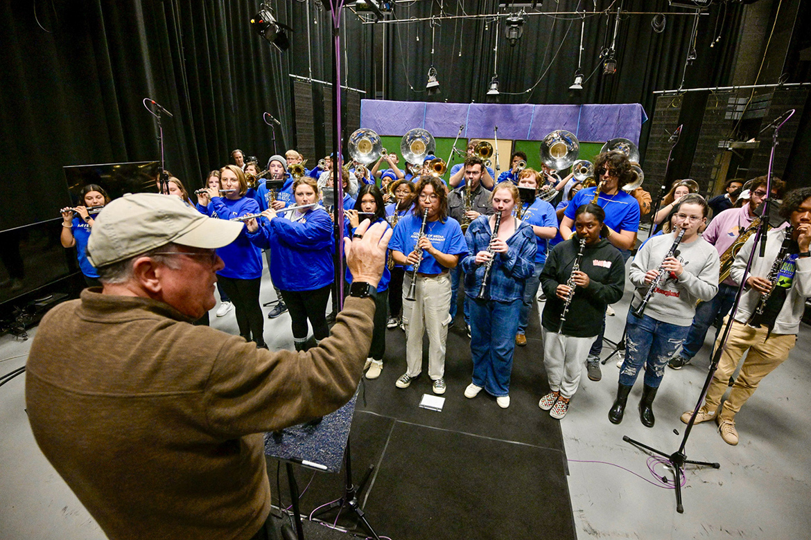 Craig Cornish, front left, music professor and director of Middle Tennessee State University’s Band of Blue, conducts the band in the TV studio at the College of Media and Entertainment on Nov. 27, 2023, as part of the university’s collaborative project to produce a new recording of the MTSU fight song. (MTSU photo by Andy Heidt)