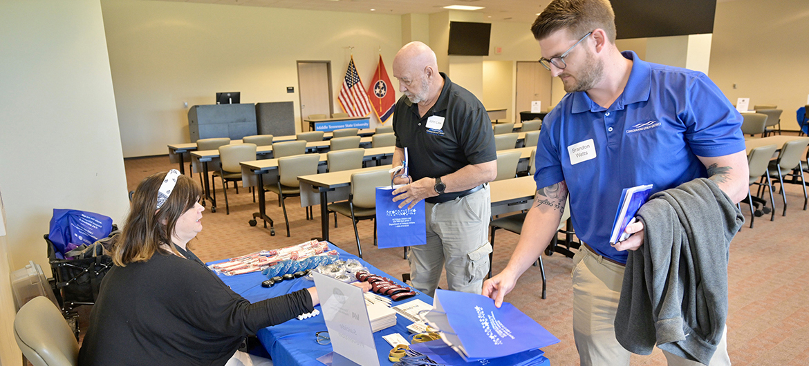 Sherri Sedgebear, left, who works in suicide prevention with Tennessee Valley Healthcare, provides information and swag for Consolidated Utility District of Rutherford County employees John Law, center, and Brandon Watts on Tuesday, April 23, during the partnership luncheon/information session for utility employee- veterans sponsored by Middle Tennessee State University and Middle Tennessee Electric. The event, held in the MTSU Miller Education Center on Bell Street in Murfreesboro, Tenn., assisted employee veterans with learning about VA benefits’ opportunities. Watts is an MTSU alumnus who already has gone through the Charlie and Hazel Daniels Veterans and Military Family Center process. (MTSU photo by Andy Heidt)