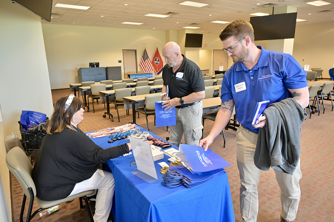 Sherri Sedgebear, left, who works in suicide prevention with Tennessee Valley Healthcare, provides information and swag for Consolidated Utility District of Rutherford County employees John Law, center, and Brandon Watts on Tuesday, April 23, during the partnership luncheon/information session for utility employee- veterans sponsored by Middle Tennessee State University and Middle Tennessee Electric. The event, held in the MTSU Miller Education Center on Bell Street in Murfreesboro, Tenn., assisted employee veterans with learning about VA benefits’ opportunities. Watts is an MTSU alumnus who already has gone through the Charlie and Hazel Daniels Veterans and Military Family Center process. (MTSU photo by Andy Heidt)