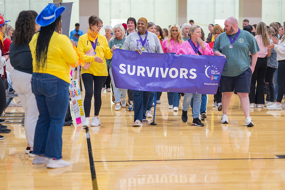 Cancer survivors including guest speaker Taylor Blanton, right, of Woodbury, Tenn., hold the American Cancer Society Relay for Life “SURVIVORS” banner while leading the parade around the Campus Recreation Center gym floor on the Middle Tennessee State University campus in Murfreesboro, Tenn. The annual MTSU Relay for Life fundraising event was held March 22, attracting about 250 people for a variety of activities. (MTSU photo by Cat Curtis Murphy)
