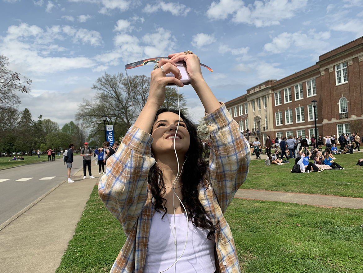 Middle Tennessee State University junior microbiology major Victoria Gamez of Winchester, Tenn., takes eclipse photos with her cell phone near the MTSU Observatory on campus in Murfreesboro, Tenn.  An estimated 300 people gathered in that area on the west side of campus. (MTSU photo by Randy Weiler)