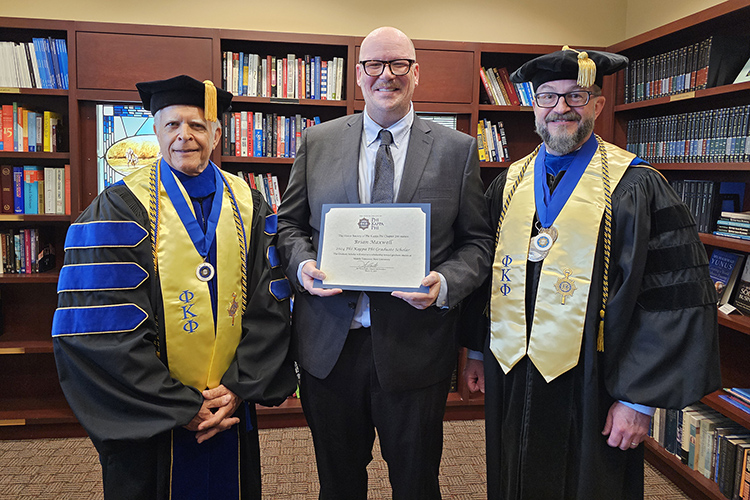 David Foote, left, president of the MTSU Chapter 246 of Phi Kappa Phi and a management professor in the Jones College of Business, and Philip E. Phillips, right, immediate past president of the Chapter and MTSU Honors College associate dean, present the 2024 PKP Graduate Scholar Award to video and film production major Brian Maxwell, center, an Honors Buchanan Transfer Fellow. (MTSU photo by Robin E. Lee)