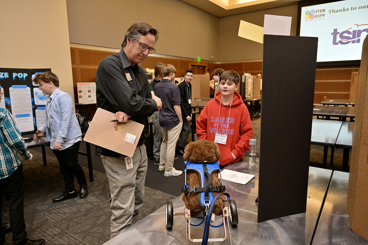 Liberty Creek Middle School student Ritchie McClellan, 12, right, of Hendersonville, Tenn., talks about his “Dog Wheeler” research project with event judge Chris Fleming of Loretto, Tenn., associate director in the special projects division (including Ag in the Classroom) with Farm Bureau. Their interaction happened Wednesday, April 3, in the Middle Tennessee State University Student Union Ballroom during the annual Middle Tennessee STEM Innovation Hub STEM Expo on the MTSU campus in Murfreesboro, Tenn. (MTSU photo by Andy Heidt)
