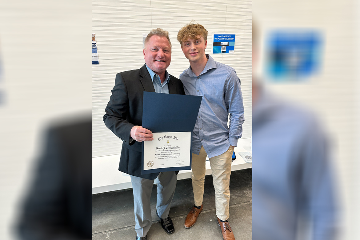 Middle Tennessee State University School of Journalism and Strategic Media instructor Dan Eschenfelder, shown here with his son Cameron, holds up the certificate noting his induction into the Phi Kappa Phi Honor Society while pursuing his master’s degree in liberal arts. Not only are the Eschenfelders father and son, they are also fraternity brothers, with Cameron joining the same fraternity as his dad, Sigma Pi. The two were able to attend numerous fraternity events together while working on the degrees they received a day apart during MTSU’s spring commencements May 3-4. (Photo courtesy of Dan Eschenfelder)