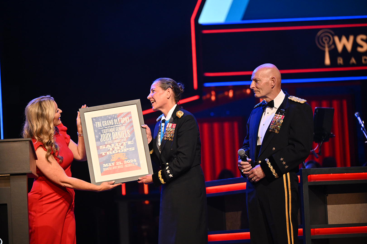 Lt. Gen. Jody Daniels, center, commanding general of the U.S. Army Reserve, accepts a commemorative poster from Grand Ole Opry announcer Kelly Sutton during the Opry’s Salute the Troops celebration held Tuesday, May 21, at the Opry in Nashville, Tenn. Looking on at right is retired Lt. Gen. Keith Huber, Middle Tennessee State University’s senior adviser for veterans and leadership initiatives who introduced Daniels from the stage and hosted her at a campus visit earlier that day. (MTSU photo by James Cessna)