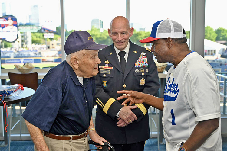 World War II Navy veteran and D-Day survivor Bill Allen, of Murfreesboro, Tenn., left, chats with Middle Tennessee State University President Sidney A. McPhee, right, at the Nashville Sounds’ special Military Appreciation Night game Thursday, June 6, at First Horizon Park in Nashville, Tenn. Looking on, center, is retired Army Lt. Gen. Keith Huber, MTSU senior adviser for veterans and leadership initiatives, who joined McPhee in inviting the 99-year-old Allen, who was a special guest for the game. It was also True Blue Night at the Sounds. (MTSU photo by James Cessna)