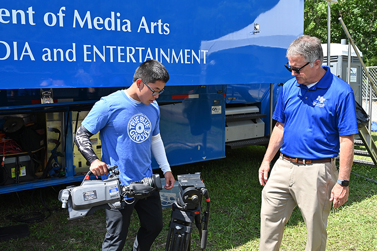 MTSU Provost Mark Byrnes, right, watches College of Media and Entertainment student Justin Kuddar Wednesday, June 12, at the Bonnaroo Music and Arts Festival in Manchester, Tenn., as students prepare to broadcast concerts from the festival grounds on two of its five stages for the four-day event. (MTSU photo by James Cessna)