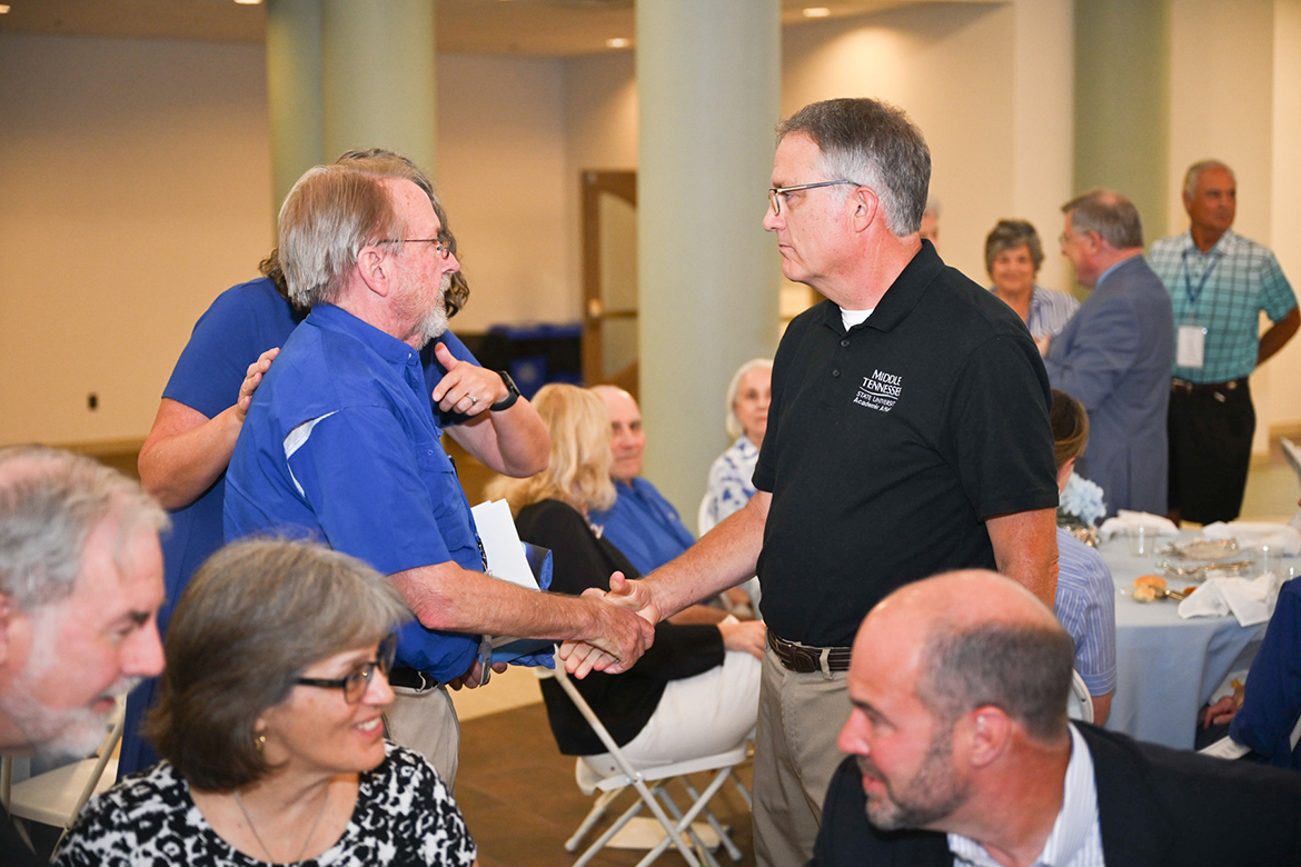 As others enjoy reminiscing about their time in college, Middle Tennessee State University Provost Mark Byrnes, right, greets a university alumnus attending the dinner on Wednesday, June 26, for the 15th annual Alumni Summer College featuring the theme of the future of analytics and artificial intelligence, or AI. More than 70 alumni attended summer college this year. (MTSU photo by James Cessna)