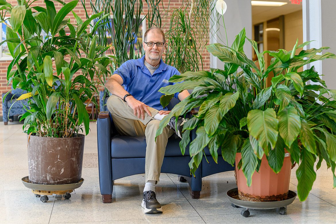 James Hart, a math professor at Middle Tennessee State University in Murfreesboro, Tenn., is seated among several of his plants temporarily on display in Cope Administration Building on campus while renovations are underway in its former home at Kirksey Old Main, where his office was located. Surrounding the professor are, from left, a ti plant that he purchased when he was 8, two ponytail palms in back, and a peace lily that came from the funeral of his grandmother. (MTSU photo by J. Intintoli)