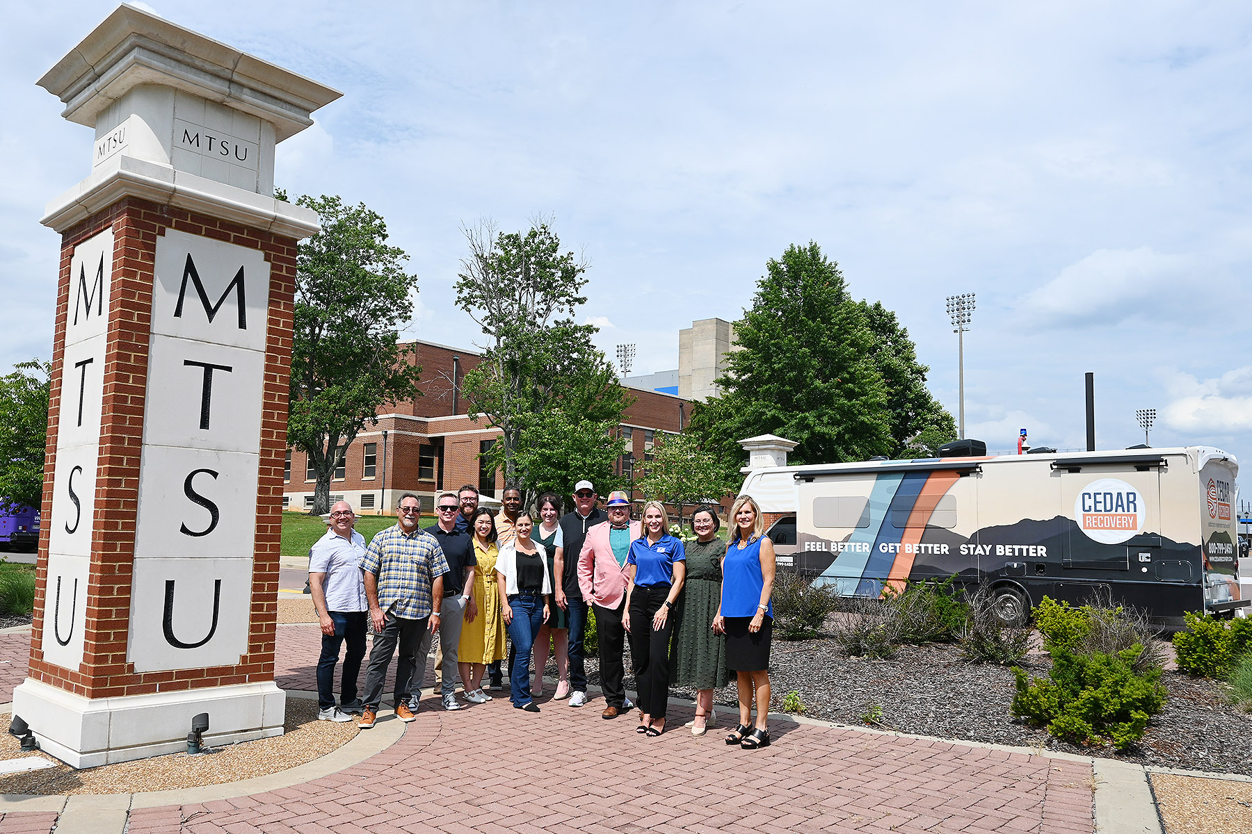 Representatives from the Center for Health and Human Services at Middle Tennessee State University and the Cedar Recovery addiction treatment company gather on the university campus in Murfreesboro, Tenn., to celebrate the new Cedar Recovery mobile addiction treatment clinic in the background that is being funded by a federal grant garnered by the MTSU center. (MTSU photo by Nancy DeGennaro)