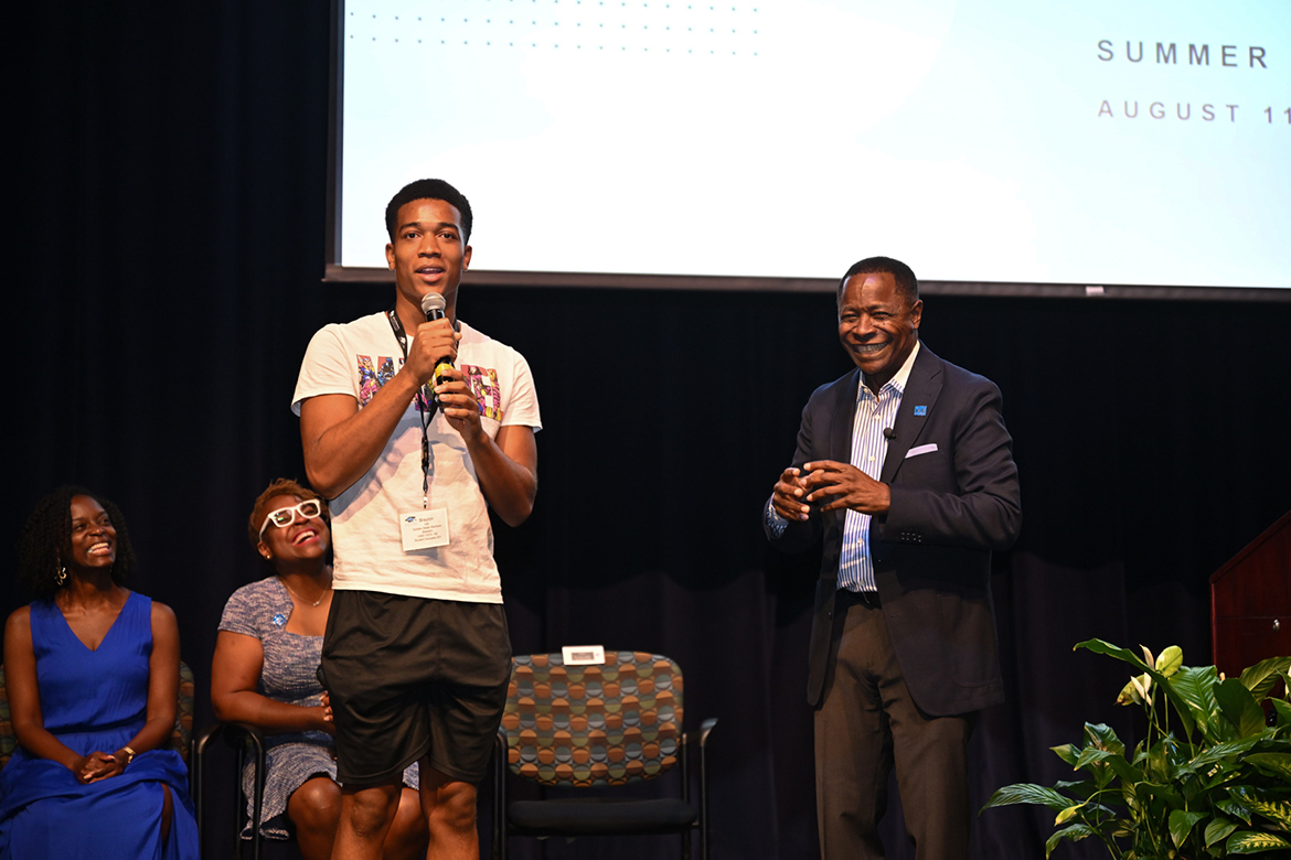 Braylon Hill, center, of Mt. Juliet, Tenn., makes Middle Tennessee State University President Sidney A. McPhee, right, and audience members laugh recently during the welcome ceremony for the fall 2024 Scholars Academy Freshman Summer Institute inside Tucker Theatre in Murfreesboro, Tenn. Seated on stage behind them, from left, are College of Education Dean Neporcha Cone and Vice President of Student Affairs and Dean of Students Khalilah Doss. Hill, who received a $100 book scholarship from the president for knowing McPhee’s middle name (Anthony), and more than 140 freshmen and transfer students spent 12 days becoming acquainted with campus life. (MTSU photo by James Cessna)