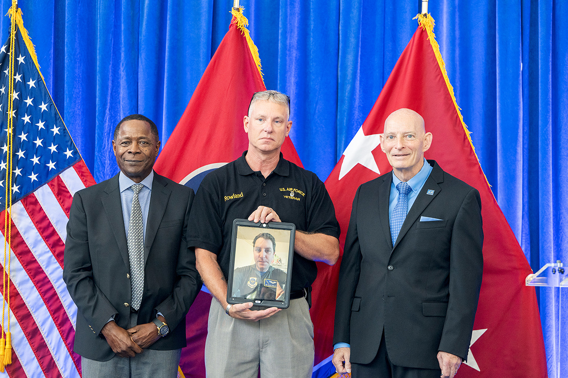 U.S. Air Force veteran Bryan Rowland, center, holds a tablet showing his son, Shawn Rowland, a graduating Middle Tennessee State University senior veteran on active duty with the Air Force in Spokane, Wash., as he receives special acknowledgement from MTSU President Sidney A. McPhee, left, and Keith M. Huber, senior adviser for veterans and leadership initiatives, at the summer Graduating Veterans Stole Ceremony Friday, Aug. 9, at the Miller Education Center on Bell Street in Murfreesboro, Tenn. For different reasons, it has taken Shawn Rowland 14 years to graduate from the school he calls “my university” with a political science (pre-law concentration) degree. (MTSU photo by Andy Heidt)