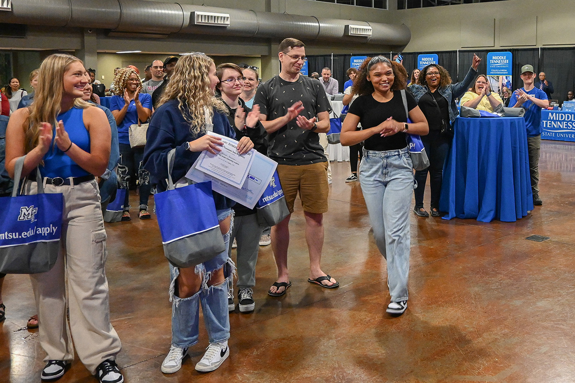 Now a Middle Tennessee State University freshman, Aniah Kidd, right, smiles on her way to accept her scholarship won during a drawing at MTSU’s True Blue Tour recruitment stop for prospective students at the Wilma Rudolph Event Center in Clarksville, Tenn., in September 2023, as her mother, with hands raised, cheers her on in the background. The 2024 edition of the tour will return to Clarksville Sept. 23. (MTSU file photo by Stephanie Wagner)