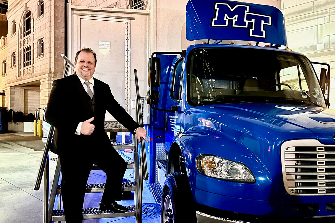 In this undated photo, Middle Tennessee State University electronic media communications alumnus Nic Dugger poses on the steps of the College of Media and Entertainment’s mobile production lab, often referred to as “The Truck,” outside the Schermerhorn Symphony Center in downtown Nashville, Tenn. (Photo submitted)