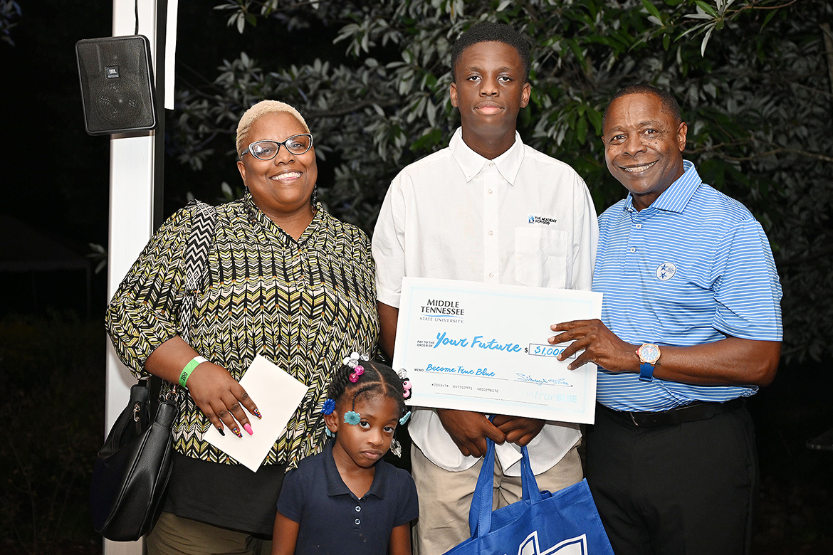 Middle Tennessee State University President Sidney A. McPhee, right, awards a $1,000 scholarship to Brandyn Warfield, middle, a senior at Academy for God in Old Hickory, Tenn., as his mother, Chantell Warfield, joins them on stage at the Murfreesboro, Tenn., university’s True Blue Tour student recruitment event held Wednesday, Sept. 18, at the Nashville Zoo. The teenager plans to study aerospace and enroll in the renowned Professional Pilot Program. (MTSU photo by James Cessna)