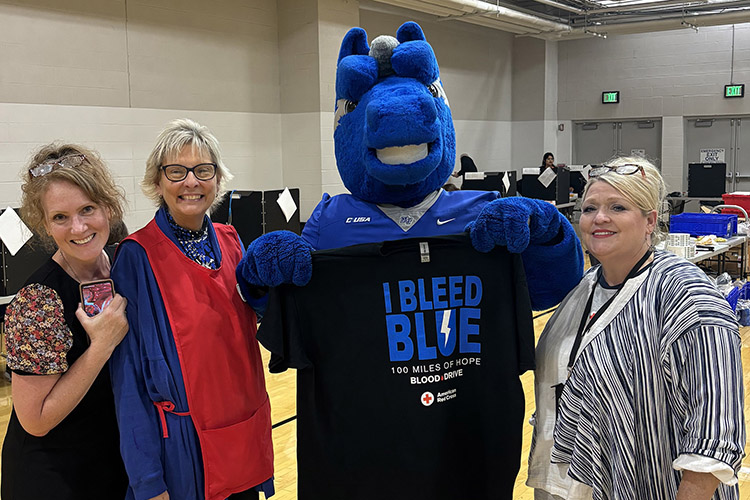 Middle Tennessee State University faculty and American Red Cross staff pose with Lightning as he holds up the “100 Miles of Hope” MTSU-WKU blood drive competition incentive T-shirt on Monday, Sept. 9, the first day of the drive, in the Campus Recreation Center gymnasium in Murfreesboro, Tenn. Pictured, from left, are Julie Byers, American Red Cross donor recruitment account manager; Diane Turnham, MTSU deputy athletic director and senior women’s administrator; Lightning, MTSU’s mascot; and Kristi Bradley, American Red Cross collections specialist. MTSU beat WKU by collecting 405 units while WKU collected 369 units. (MTSU photo by Maddy Williams)