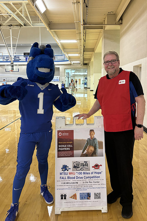 Middle Tennessee State University’s Ray Wiley, Campus Recreation associate director of facilities and longtime Red Cross volunteer, poses with MTSU mascot Lightning in front of the signage for the “100 Miles of Hope” blood drive competition on Monday, Sept. 9, the first day of the drive, in the Campus Recreation Center gymnasium in Murfreesboro, Tenn. MTSU beat WKU by collecting 405 units while WKU collected 369 units. (MTSU photo by Maddy Williams)