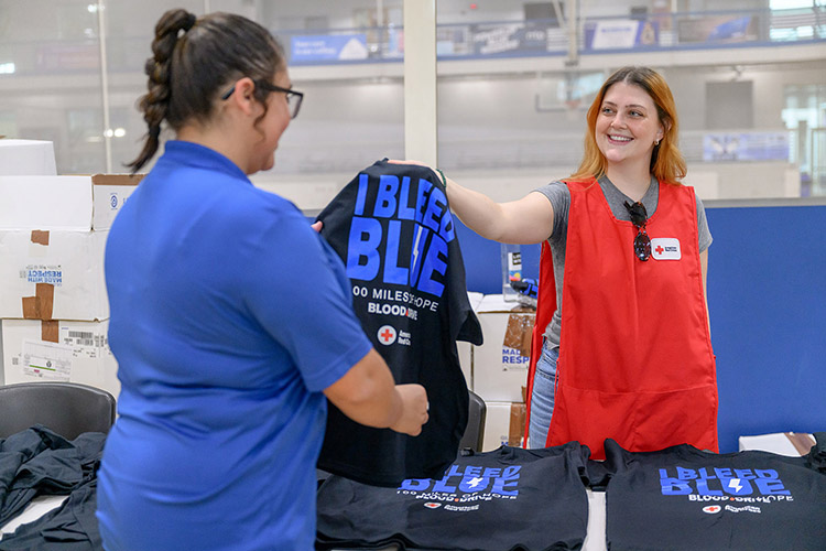 Bella Young, Campus Recreation student worker at Middle Tennessee State University, receives a “100 Miles of Hope” free T-shirt from Meagan Dodd, MTSU student volunteer, on Monday, Sept. 9, the first day of the three-day drive, in the MTSU Campus Recreation Center gymnasium in Murfreesboro, Tenn. MTSU beat Western Kentucky University by collecting 405 units while WKU collected 369 units. (MTSU file photo by J. Intintoli)