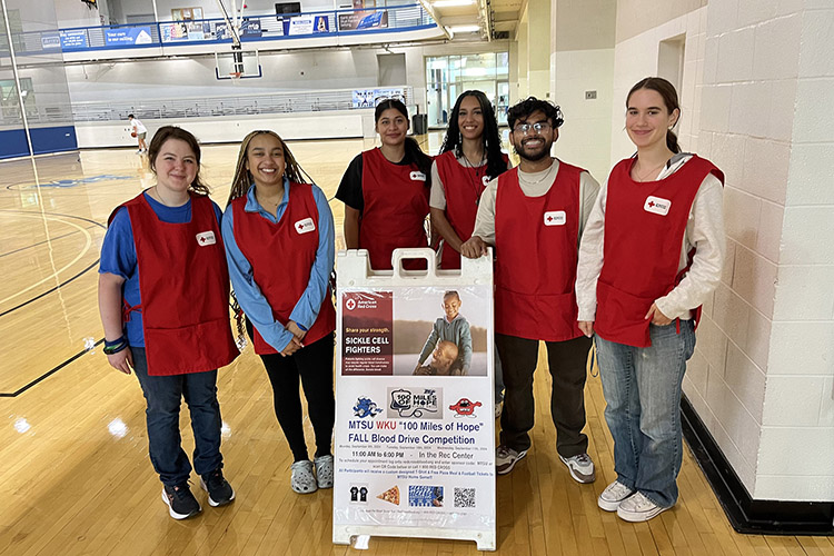 Middle Tennessee State University student blood drive volunteers stand in front of the signage for the “100 Miles of Hope” blood drive competition on Wednesday, Sept. 11, the last day of the three-day drive, inside the Campus Recreation Center gymnasium in Murfreesboro, Tenn. MTSU beat Western Kentucky University by collecting 405 units while WKU collected 369 units. (Photo submitted by Ray Wiley)