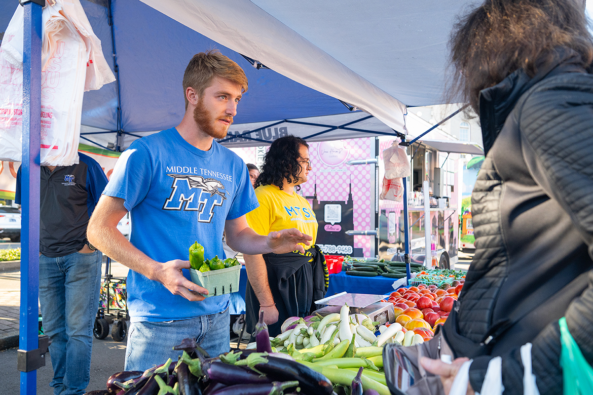 Collecting a small basket of bell peppers for a customer at the Murfreesboro Saturday Market on Oct. 12 at the Rutherford County Courthouse in downtown Murfreesboro, Tenn., Middle Tennessee State University senior plant and soil science major Tyler Lansford has emerged as the leader for more than 10 students in the MTSU Small Farm program. The group will be at the market Oct. 19 and Oct. 26 and plans to return next year. (MTSU photo by Cat Curtis Murphy)