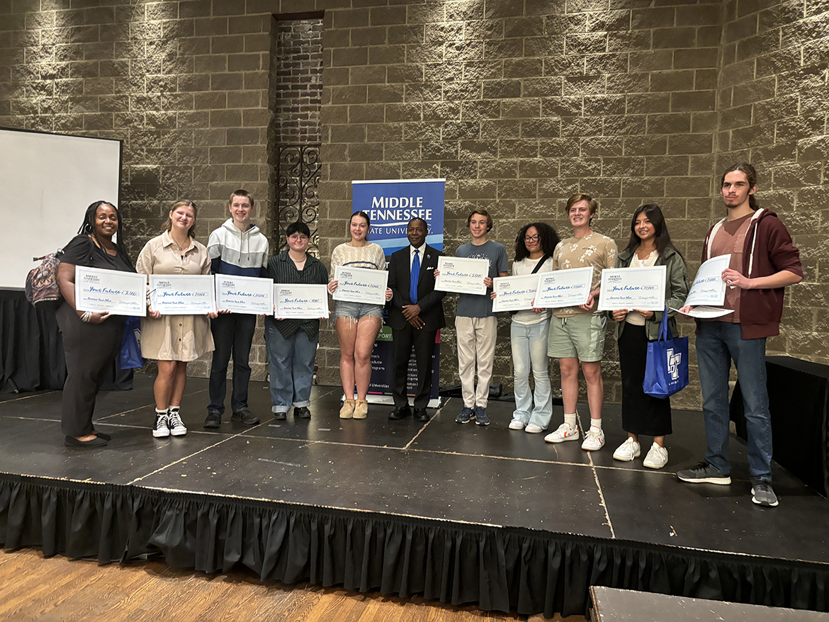 Holding “big checks” indicating scholarships they received when their names were called during a drawing, 10 Knoxville-area high school and community college students are shown with Middle Tennessee State University President Sidney A. McPhee, center, during the MTSU True Blue Tour visit to Knoxville, Tenn., Wednesday, Oct. 2, at The Foundry on the Fair Site. From left, recipients include JoEllen M. DuBose, Carolina Haywood, Toby Aurelic, Elizabeth “Paige” Hooder, Kiera Barnes, James Elliott Swann, Jadeyn Pendergrass, Ivan Colwell, Gabriella Trujillo and Jackson Zubra. (MTSU photo by Randy Weiler)