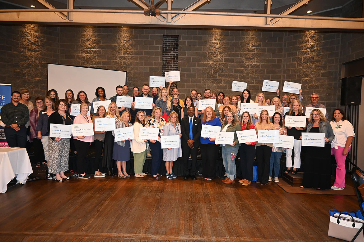 With Middle Tennessee State University President Sidney A. McPhee, front center, East Tennessee high school counselors and community college staff hold “big checks” for scholarships earmarked for students at their schools across the region Wednesday, Oct. 2, during the annual MTSU True Blue Tour stop at The Foundry on the Fair Site in Knoxville, Tenn. MTSU awarded more than $194,000 in scholarships to more than 70 schools. (MTSU photo by Andrew Oppmann)